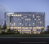 the large hotel sits near a grassy field in an illuminated area with several windows on the exterior