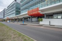 modern office building with red and white covering on front side of street on cloudy day