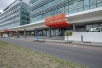 modern office building with red and white covering on front side of street on cloudy day