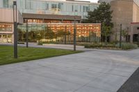 a person rides a skateboard down an asphalt road in front of a building with glass on it