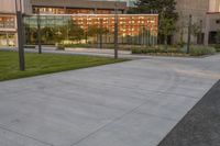 a person rides a skateboard down an asphalt road in front of a building with glass on it