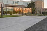 a person rides a skateboard down an asphalt road in front of a building with glass on it