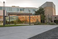 a person rides a skateboard down an asphalt road in front of a building with glass on it