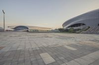 an empty paved space at dusk with building in the background of it and stairs up to it