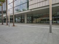 an empty square next to a building with trees and glass windows on both sides of the building