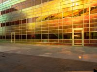 there is an empty sidewalk in front of a large building with glass walls and stairs