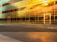 there is an empty sidewalk in front of a large building with glass walls and stairs