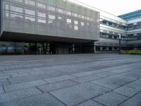 a walkway is shown outside an office building with windows in front of it and light reflecting off the facade on a dark day