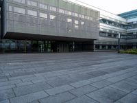 a walkway is shown outside an office building with windows in front of it and light reflecting off the facade on a dark day