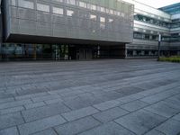 a walkway is shown outside an office building with windows in front of it and light reflecting off the facade on a dark day