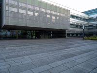 a walkway is shown outside an office building with windows in front of it and light reflecting off the facade on a dark day