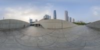 the circular mirror is sitting in front of some buildings and skyscrapers near the water