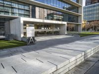 a large building with glass windows in the middle of it's sidewalk and grassy area