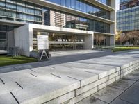 a large building with glass windows in the middle of it's sidewalk and grassy area