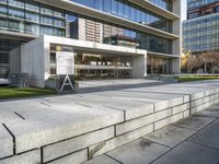 a large building with glass windows in the middle of it's sidewalk and grassy area