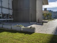 a concrete flowerbed in the grass between two buildings on the same building, with grass beside