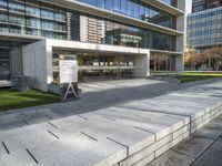 a large stone bench that is by some building in a city, which is situated between concrete block steps and sidewalk