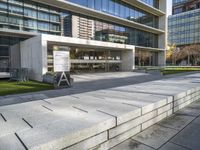 a large stone bench that is by some building in a city, which is situated between concrete block steps and sidewalk