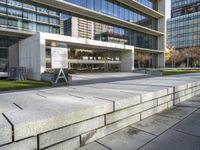 a large stone bench that is by some building in a city, which is situated between concrete block steps and sidewalk