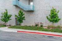 a parking meter in front of a building on the corner of an intersection with a tree and grass