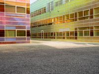 an empty parking lot and some tall buildings with reflective windows that is colorfully colored