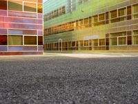 an empty parking lot and some tall buildings with reflective windows that is colorfully colored