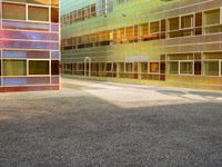 an empty parking lot and some tall buildings with reflective windows that is colorfully colored