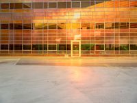 an empty parking lot with a large building behind it and a sun flare out from the window