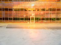 an empty parking lot with a large building behind it and a sun flare out from the window