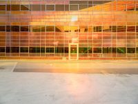 an empty parking lot with a large building behind it and a sun flare out from the window