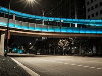 the illuminated walkway leads to an elevated walkway over an empty street at night with cars on it