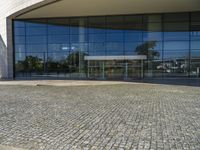 two people walking past a very large building with big glass doors and windows that look like a museum