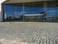 two people walking past a very large building with big glass doors and windows that look like a museum