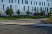 a city street surrounded by grass and tall buildings at the end of a street there is a paved pathway in front of the building