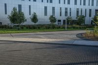 a city street surrounded by grass and tall buildings at the end of a street there is a paved pathway in front of the building