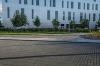 a city street surrounded by grass and tall buildings at the end of a street there is a paved pathway in front of the building