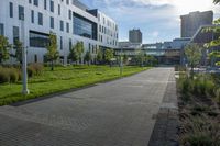 a city street surrounded by grass and tall buildings at the end of a street there is a paved pathway in front of the building