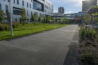 a city street surrounded by grass and tall buildings at the end of a street there is a paved pathway in front of the building