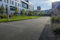 a city street surrounded by grass and tall buildings at the end of a street there is a paved pathway in front of the building