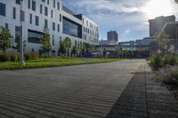 a city street surrounded by grass and tall buildings at the end of a street there is a paved pathway in front of the building