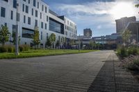 a city street surrounded by grass and tall buildings at the end of a street there is a paved pathway in front of the building