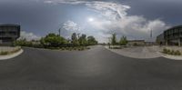 the view from a fish eye lens of buildings and trees in a roundabout on a cloudy day