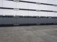 an empty sidewalk in front of a building with lots of windows on it's sides