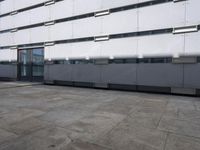 an empty sidewalk in front of a building with lots of windows on it's sides