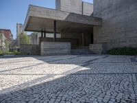 the building is made from concrete with cobblestone street below it and several other steps to