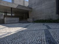 the building is made from concrete with cobblestone street below it and several other steps to