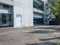 a sidewalk outside a building with no people walking or running through the building, some grass and trees