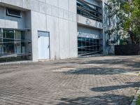 a sidewalk outside a building with no people walking or running through the building, some grass and trees