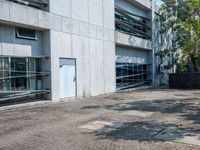 a sidewalk outside a building with no people walking or running through the building, some grass and trees