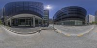 a street corner and a wide lens fish eye view of a building that is very tall and has several windows